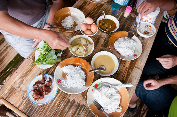Khanom Chin, a traditional Thai dish consisting of fresh thin rice noodles served with various curries, gravies, and toppings like hard-boiled eggs and fresh herbs.