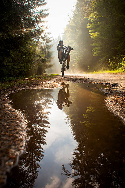 Rear view of a mountain biker racing downhill, debris and dirt flying from rear wheel. Man shredding on mountainbike, back view.