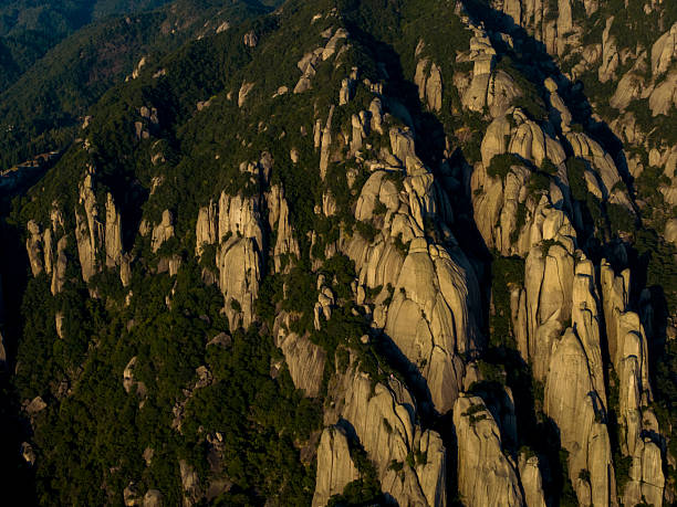 A breathtaking view of rugged mountain peaks bathed in warm sunlight, surrounded by lush greenery. The serene atmosphere suggests tranquility and natural beauty. Potential usage includes nature photography, travel brochures, or environmental campaigns.
