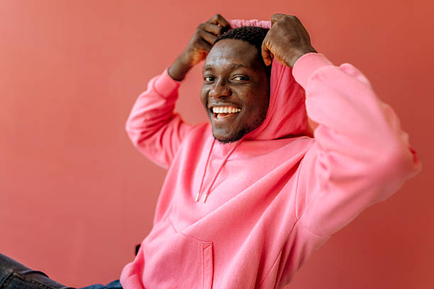 istock Young black man smiles while sitting against a pink backdrop in a playful moment 2250177464