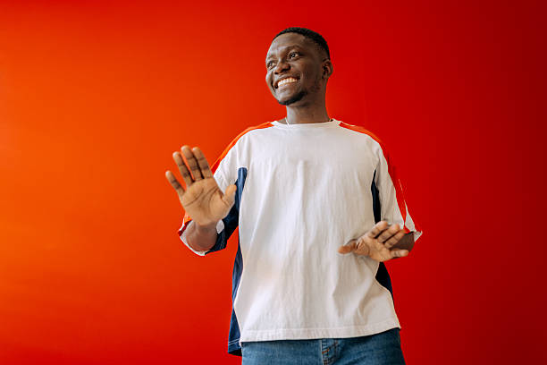 istock Young black man enjoys playful moment in studio against bright background while smiling and expressing joy in vibrant setting 2250179236