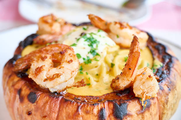 Roasted pumpkin filled with creamy pasta, succulent shrimp, and fresh parsley, creating a gourmet seafood dish