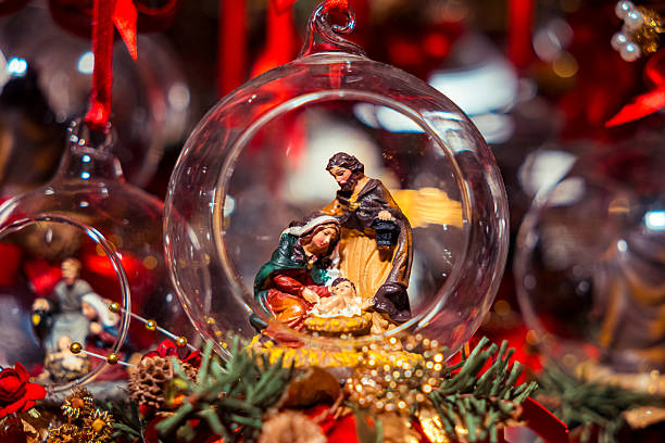 Detailed nativity figurines displayed inside a clear glass ball, featuring Mary, Joseph, and baby Jesus as a festive Christmas decoration.