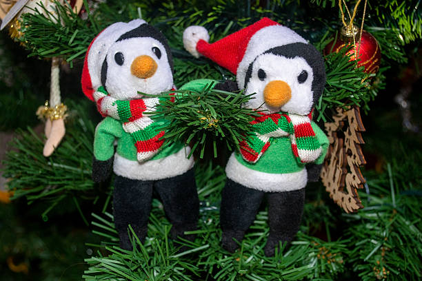 Two decorative fabric penguin ornaments placed on a green Christmas tree. Festive holiday decor with soft textile details and a charming winter theme