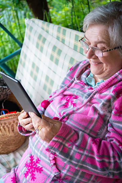 istock Smiling senior woman using digital tablet in the summer back yard 2250210553