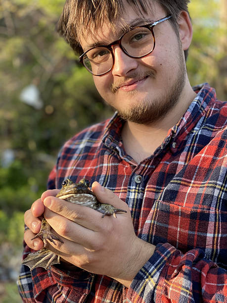 istock Young man holding large bullfrog 2250212443