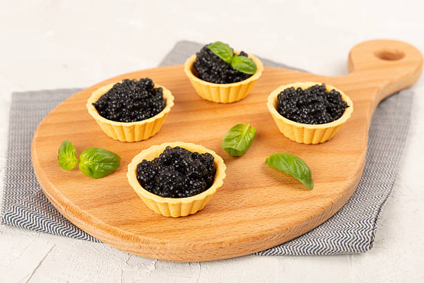 istock Tartlets with black caviar served on on wooden table 2250214518