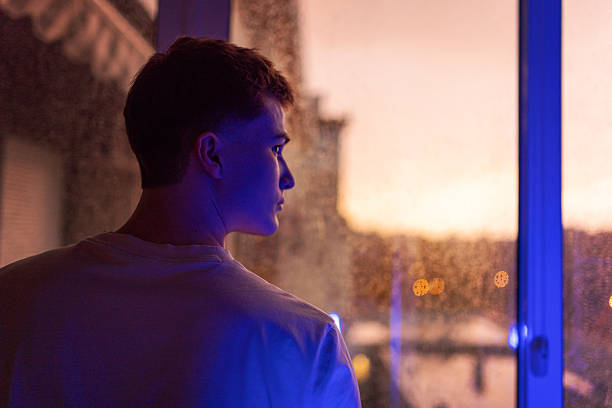 Man looking out of window at rainy day.