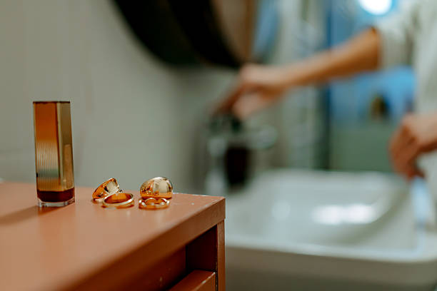 Hair claw clip and perfume on bathroom table, woman is washing hands in the background