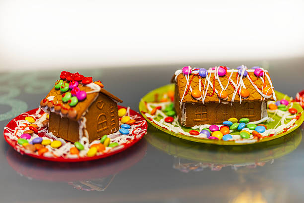 Two colorful gingerbread houses decorated with icing and candy stand festive and bright on plates. Sweden.