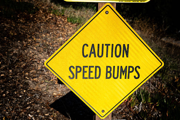 A bright yellow sign alerts drivers and pedestrians to slow down for speed bumps, ensuring safety