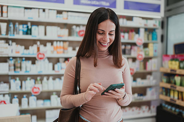 istock Smiling woman using smartphone in pharmacy 2250234599