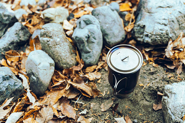 A stainless camping pot placed on forest ground surrounded by rocks and fallen leaves. The warm outdoor atmosphere captures the simplicity of camp cooking, bushcraft, and minimal outdoor gear. Ideal for themes related to camping, outdoor lifestyle, hiking, adventure, and wilderness cooking.