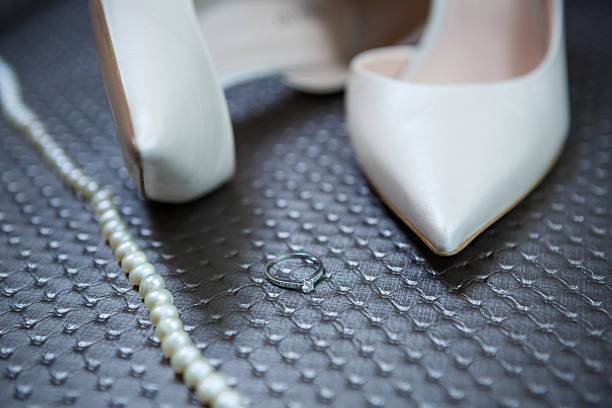 Close up of bride's pearl earrings, necklace and high heel shoes for wedding