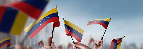 istock Venezuela flags in their hands on a blurred urban background 2250256328
