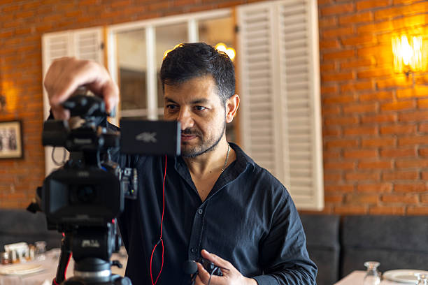 istock Male videographer professionally filming content with a 4k video camera on a tripod, creating digital media for a restaurant or business enterprise 2250261656