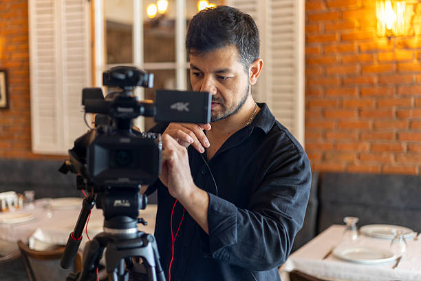 istock Professional videographer working with camera on a tripod, recording video in a restaurant setting for commercial production or content creation 2250261680