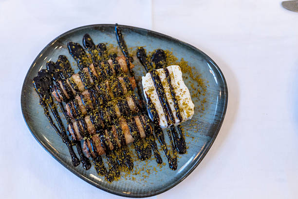 Turkish dessert rolls with melted chocolate sauce, topped with crushed pistachio and creamy ice cream, serving a delightful sweet course at a fine dining restaurant