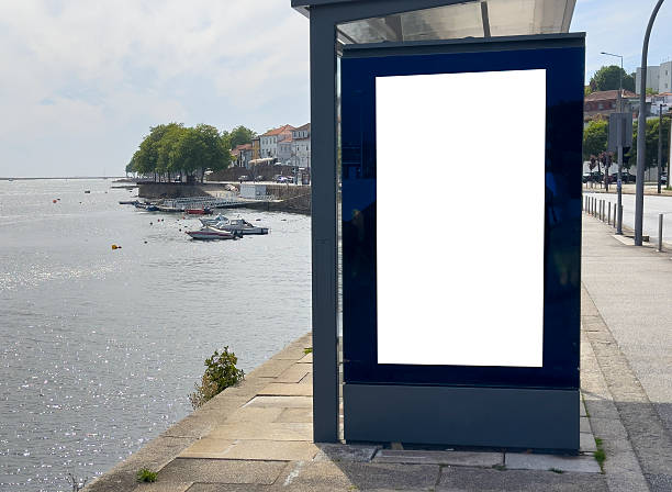 istock Billboard sign stands at waterfront bus station. Blank modern vertical panel with glass frame offers 2250262514
