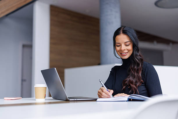 istock Woman writing in notebook while working on laptop 2250265617
