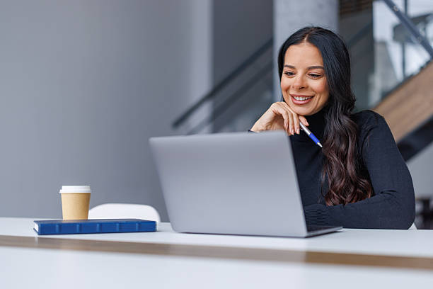 istock Professional woman smiling, working on laptop in modern office 2250265626