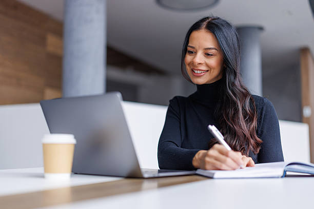 istock Woman writing notes working on laptop with coffee 2250265644