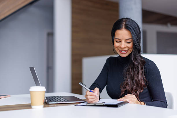 istock Happy woman writing on a clipboard in modern office 2250265815