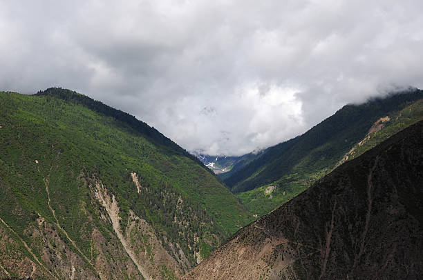 A mountain valley with lush green slopes under a cloudy sky, showcasing natural mountain landscape.