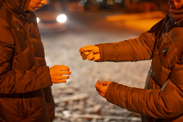 istock Two individuals carefully pass tiny item in quiet city night scene 2250271989