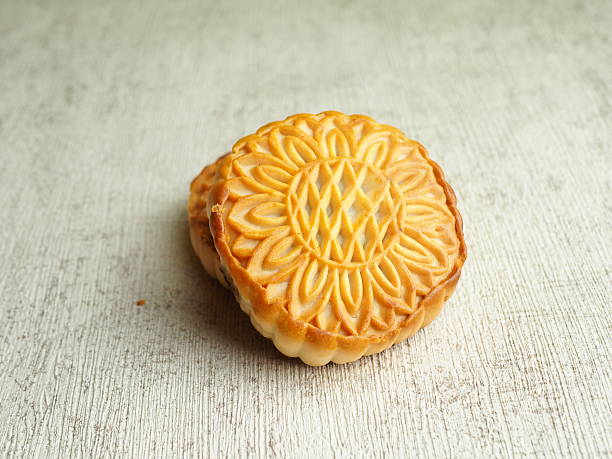 Close-up captures two intricately designed, golden-brown mooncakes stacked, exhibiting a comforting and inviting mood with their