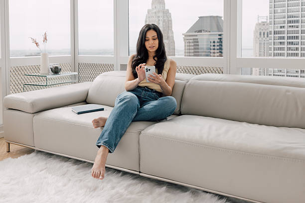 istock Woman sitting casually on sofa in sunny Manhattan apartment reading notebook 2250274731