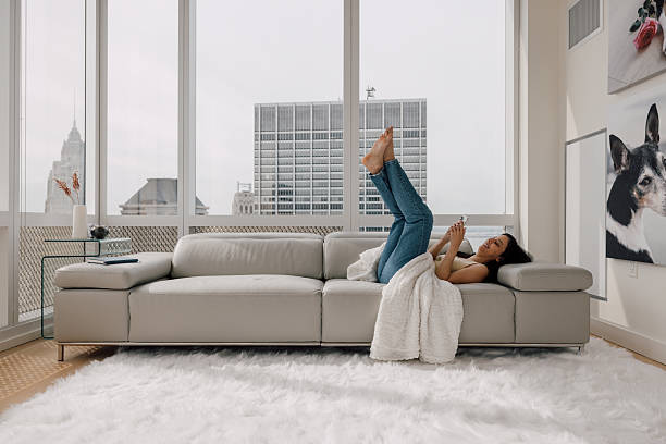 istock Woman playfully stretching on sofa inside bright Manhattan high-rise apartment 2250274792