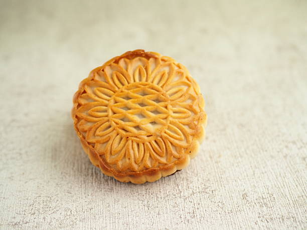istock Golden, textured mooncake sits elegantly on a light surface, showcasing its intricate floral design. 2250275118
