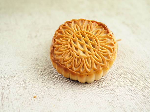 istock An intricately patterned mooncake rests on a textured surface, its golden-brown crust detailed with floral designs that suggest tradition and 2250275499
