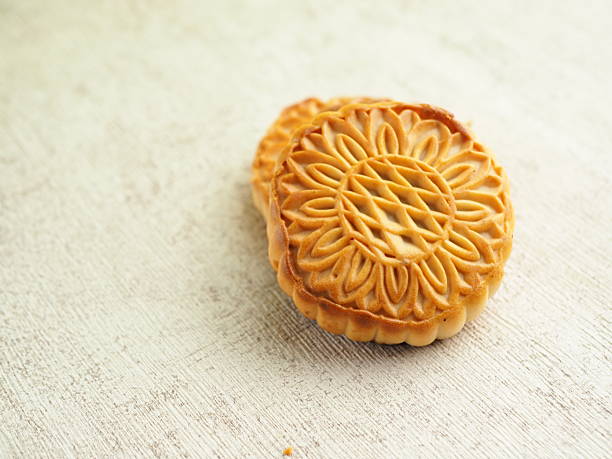 istock Two traditional mooncakes with intricate floral design are placed on textured surface in warm light. 2250275644