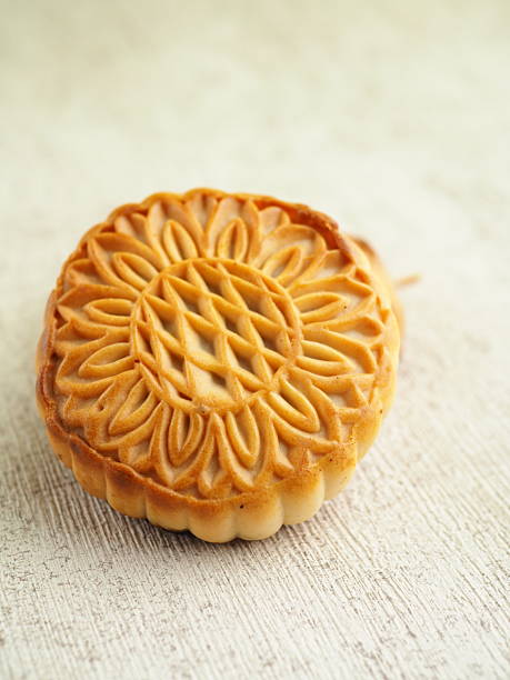 istock A single, golden mooncake with intricate floral design resting on a textured surface, top view 2250275687