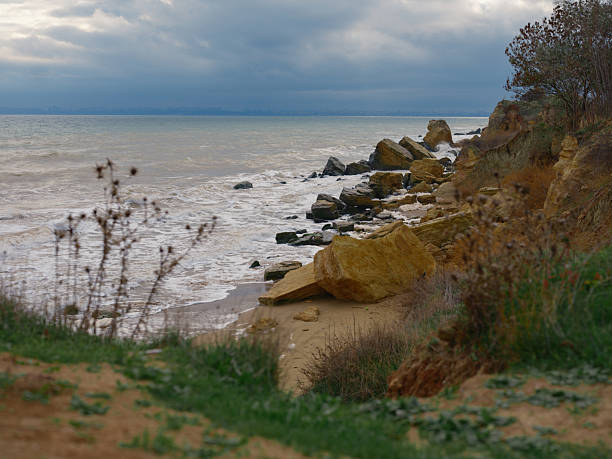 Moody landscape Black Sea coast near Odessa Fontanka. Rocky beach, crashing waves, dramatic cloudy sky. Erosion, wild nature, natural beauty, autumn atmosphere.