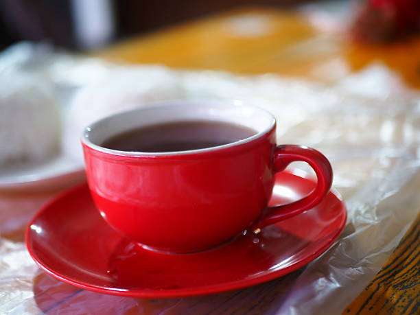 istock Vibrant red teacup on a saucer holds steaming beverage, inviting warmth in a bright setting. 2250276255