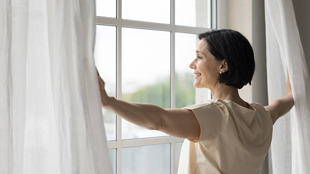 istock Side view rested middle-aged woman opening curtains 2250278710