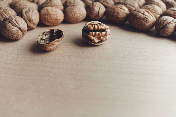 Organic walnuts coming out of a paper bag shot on rustic wooden table. The composition is at the left of an horizontal frame leaving useful copy space for text and/or logo at the right. Predominant color is brown. High resolution 42Mp studio digital capture taken with SONY A7rII and Zeiss Batis 40mm F2.0 CF lens