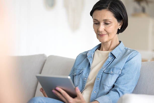 istock Mature woman working on tablet seated on cozy couch 2250284045