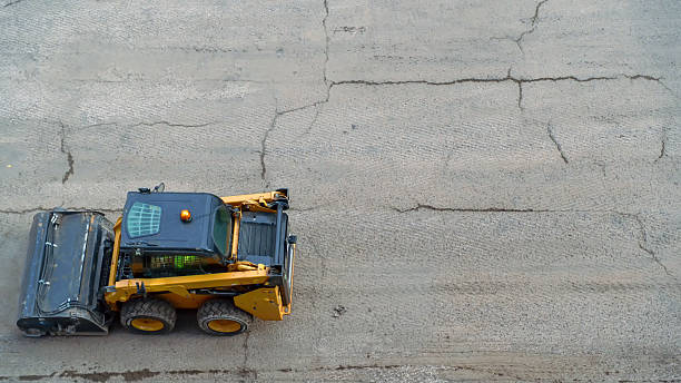 istock Skid steer loader with broom attachment preparing asphalt road for repair 2250285599