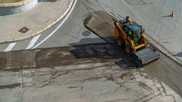istock Skid steer loader with attachment working on a damaged asphalt road surface 2250285626