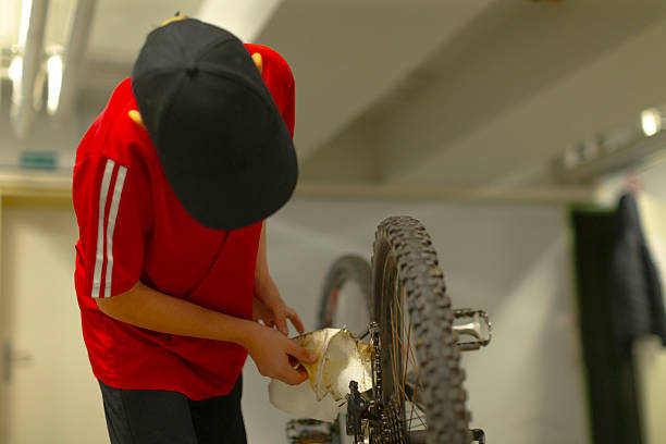 Juvenile carefully organizes bicycle within dark parking area for riding