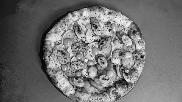 High-contrast black and white shot highlighting the rustic surface of a delicious handmade pizza.