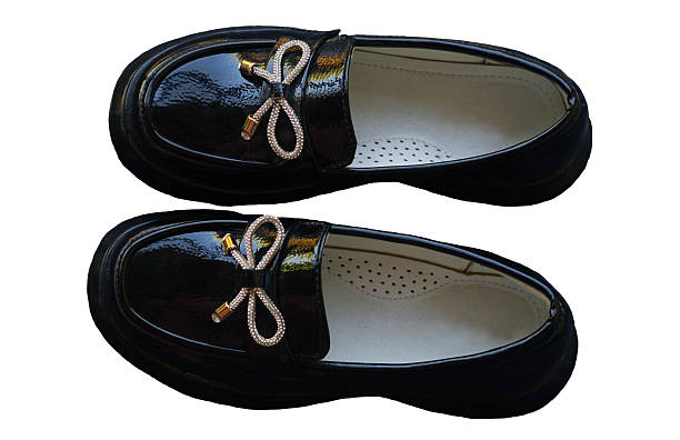 Shiny black girls' shoes stand on a white background