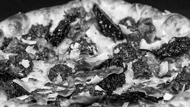 High-contrast black and white image capturing the appetizing surface of a gourmet pizza.