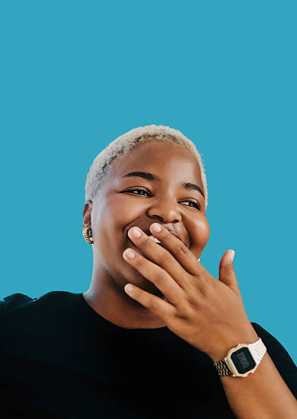 istock Young Black Woman Laughing With Hand Over Mouth Against Solid Blue Background 2250297413