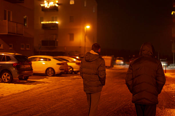 istock Two men journey silently through quiet parking area under glowing streetlights 2250299708