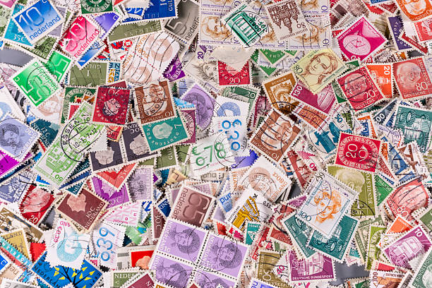 Many stamps are spread out on a surface showing different designs, colors, and denominations. The collection has stamps labeled from various countries and years.